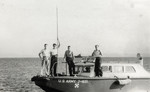 Kurt Markus poses with his friends Slutzky, Julian Burt, and Eddie Alcock on a boat while working for the American navy.