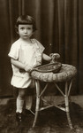 A studio portrait of two-year-old Julek 
Kracowski with a tennis racket and teddy bear.