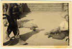 A man walks past the body of an SS guard in the Mauthuasen concentration camp following liberation.