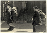 A man and a boy carry their luggage on the way to the deportation train in the Lodz ghetto.