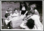 A female teacher helps young children assemble packages in a postwar OSE children's home.