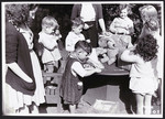 Female teachers help young children assemble packages in a postwar OSE children's home.