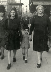 Claude walks down a street in Brussels after the war with his older sister Renee (left) and mother (right).