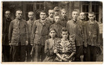 Survivors from an unidentified concentration camp, most of whom are still in uniform, pose for a group photograph.