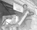 An American soldier replaces an "Adolf-Hitler-Str." street sign with a hand-made one, "Roosevelt Boulevard".