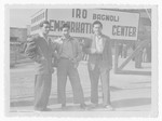 Three Jewish DPs pose in front of the sign for the IRO Embarkation Center in Bagnoli.