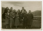A group of Jewish family and friends stands in the Skole countryside by a fence.