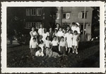 Group portrait of children and staff posing on the grounds of the Heiden children's home in Switzerland.