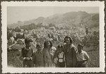 Children from the Heiden children's home and their mothers pose for a group portrait in front of view of the town.