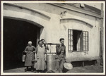 Workers carry large metal vats (perhaps containing fresh milk) on wooden poles at Ludwig Engel's farm, Edmunshof in Burgenland.