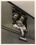 A couple and their young child look out the window of a U.S.