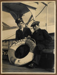 Tatsuo Osako and another crew member of the  Amakusa-maru pose on board the ship next to the life preserver.