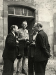 Leo Cohn (father of the donor) and three men have a conversation outside of a building, probably on a farm.