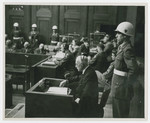 Konstantin von Neurath reads from a document during his trial for war crimes at Nuremberg.