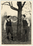 Two young men stand under a tree at the Eschwege displaced persons' camp.
