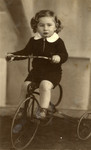 Studio portrait of Rysio Blass riding a tricycle.