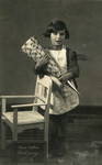 Studio portrait of Regina Birnbaum holding a cone of goodies on her first day of school in Berlin.