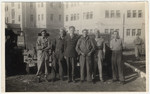 Group portrait of American soldiers and Jewish refugees standing outside next to parked military vehicles in Shanghai.