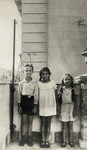 Portrait of three children standing on a porch in Palermo.