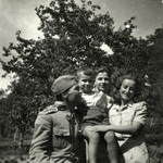 A group of friends, one in military uniform pose outside after the war.