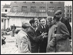 A group of Jewish men have a conversation in front of one of the ghetto factories.