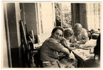 A German-Jewish family gathers around a table and looks at a picture book together.