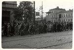 Polish men and women march down a street past a pharmacy in besieged Warsaw.