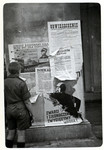 A Polish boy looks at Polish Anti-Nazi propaganda pasted onto columns in besieged Warsaw.