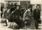 A group of women carrying large bundles march to an assembly point during a deportation action in the Lodz ghetto.