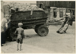 Jewish teenage boys push and pull a wagon loaded with bread to the distribution stores in the Lodz ghetto.