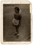 Four-year-old Agnes Biel poses on a street in Budapest in a dress and white apron.