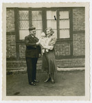 Julius and Else Gutheim stand outside a house with their infant daughter.