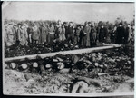 A group of survivors stares at the remains of other charred prisoners in Klooga following liberation.