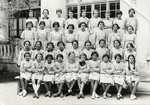 A group of Tunisian schoolgirls wearing aprons. Nadia Cohen is in the first row, third from the left.