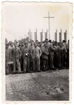 Survivors, wearing their camp uniforms, stand in front of banners in the Buchenwald concentration camp.