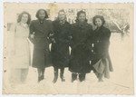 Five women stand in the snow on the grounds of the Liebenau internment camp.