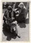 Two Jewish women sit outside in the Lodz ghetto and eat their soup ration.