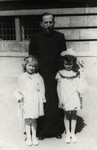 Janina Nebel (right), a Jewish child stands with a priest and another child after her First Communion.