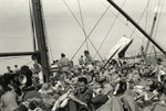 Passengers lie on the upper deck of a ship bound for Italy.
