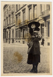 Luise 'Lilli" Lande stands on a street carrying a bouquet of roses.