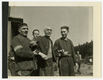 Two fellow prisoners support a weak and elderly Jewish man in the concentration camp at Holzen, Germany.