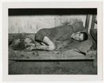 A survivor lies on a straw strewn bottom bunk in a barrack of the Langenstein-Zwieberge concentration camp.