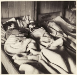 Young children sleep under a blanket in Bergen Belsen.
