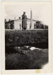 A survivor stands next to the Dachau moat and looks down on the corpses of killed SS men floating in it.