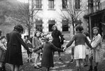 A group of children hold hands during an outside game at Aspet.