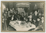 Children and women gather by a festive table for a celebration [possibly a birthday].