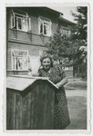 A woman stands outside a house.
