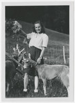 Close-up portrait of Eva Weinberger holding a bouquet of wild-flowers in one hand and a goat's collar with the other.