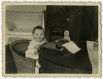 One-year-old Helen Sznajderman sits by a typewriter.