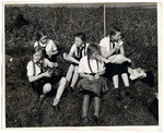 Members of the League of German Girls have a meal on a lawn.